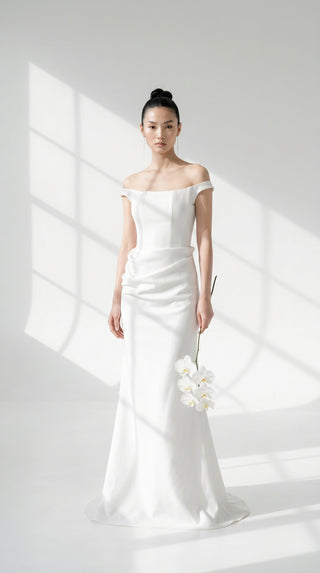An elegant dress with open shoulders and a draped skirt that combines minimalism and sophistication