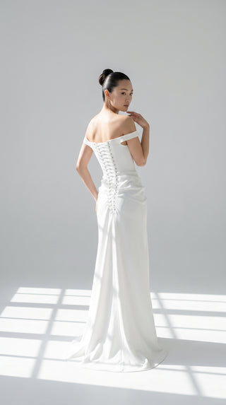 An elegant dress with open shoulders and a draped skirt that combines minimalism and sophistication