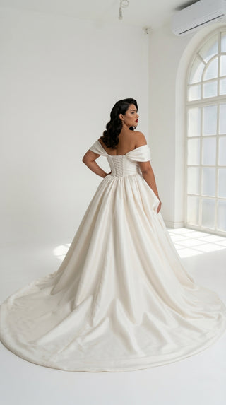 A luxurious dress with open shoulders and a lush train skirt for an elegant and majestic wedding look
