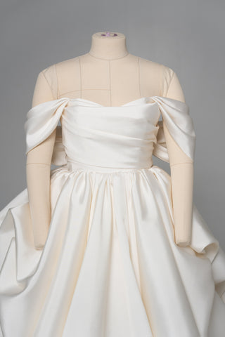 A luxurious dress with open shoulders and a lush train skirt for an elegant and majestic wedding look - designer piece by Caribis