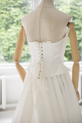 Strapless wedding dress with a basque corset, deep slit, and long train