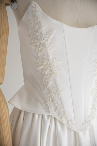 Strapless wedding dress with a basque corset, deep slit, and long train