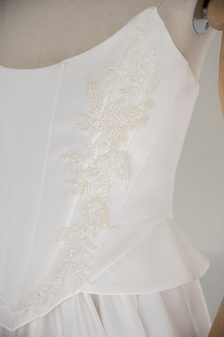 Strapless wedding dress with a basque corset, deep slit, and long train