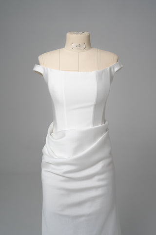 An elegant dress with open shoulders and a draped skirt that combines minimalism and sophistication
