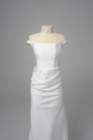 An elegant dress with open shoulders and a draped skirt that combines minimalism and sophistication