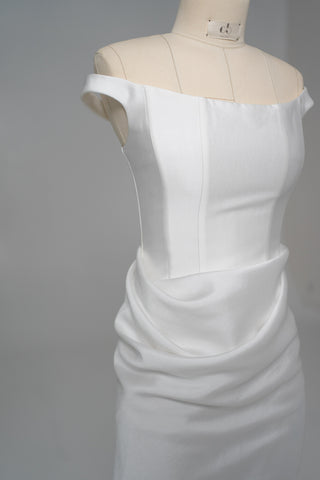 An elegant dress with open shoulders and a draped skirt that combines minimalism and sophistication