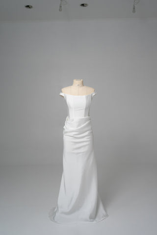 An elegant dress with open shoulders and a draped skirt that combines minimalism and sophistication