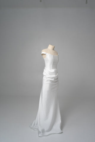 An elegant dress with open shoulders and a draped skirt that combines minimalism and sophistication