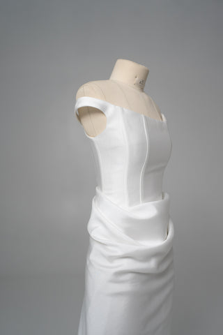 An elegant dress with open shoulders and a draped skirt that combines minimalism and sophistication