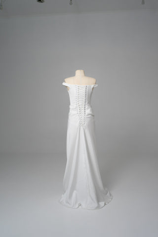An elegant dress with open shoulders and a draped skirt that combines minimalism and sophistication