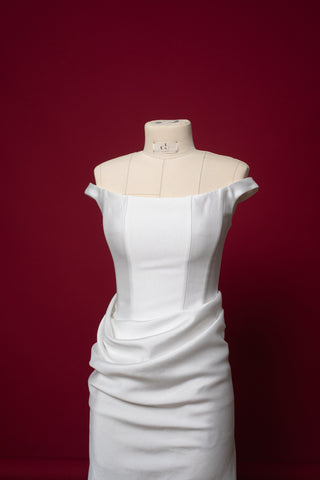 An elegant dress with open shoulders and a draped skirt that combines minimalism and sophistication