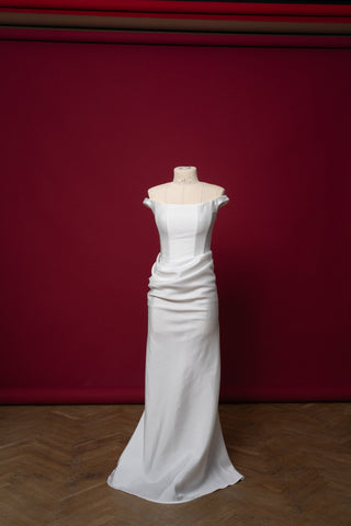 An elegant dress with open shoulders and a draped skirt that combines minimalism and sophistication
