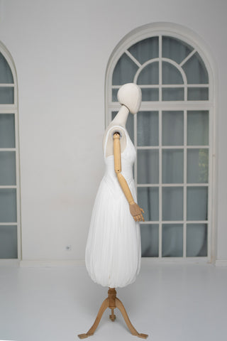 A light dress with draping and an open back that combines femininity and comfort