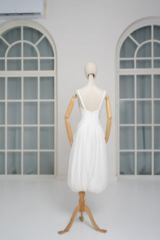 A light dress with draping and an open back that combines femininity and comfort