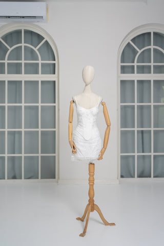 A luxurious lace mini dress with a corset base and hand-finished pearls, creating a festive and refined silhouette