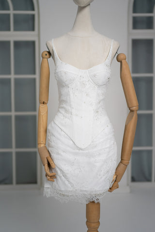 A luxurious lace mini dress with a corset base and hand-finished pearls, creating a festive and refined silhouette