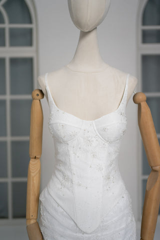 A luxurious lace mini dress with a corset base and hand-finished pearls, creating a festive and refined silhouette