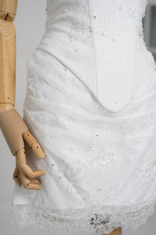 A luxurious lace mini dress with a corset base and hand-finished pearls, creating a festive and refined silhouette