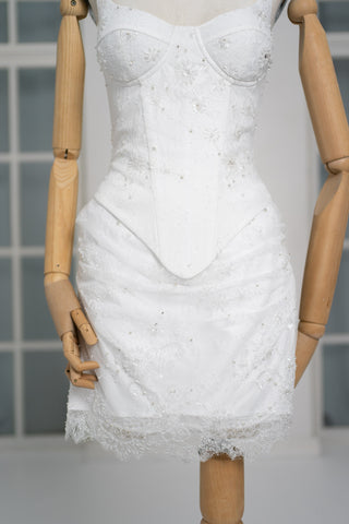 A luxurious lace mini dress with a corset base and hand-finished pearls, creating a festive and refined silhouette