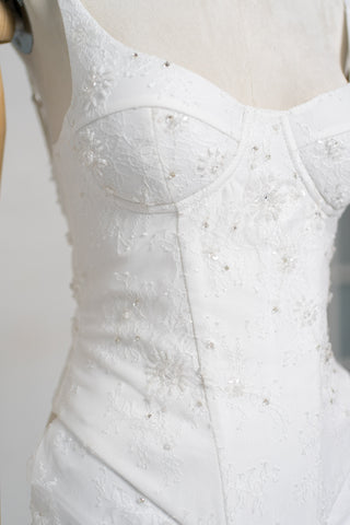 A luxurious lace mini dress with a corset base and hand-finished pearls, creating a festive and refined silhouette