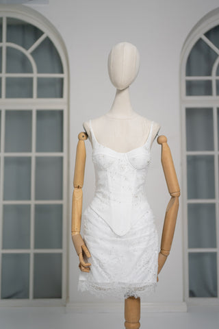 A luxurious lace mini dress with a corset base and hand-finished pearls, creating a festive and refined silhouette