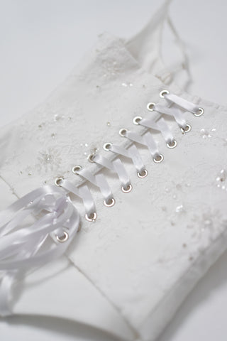 A luxurious lace mini dress with a corset base and hand-finished pearls, creating a festive and refined silhouette