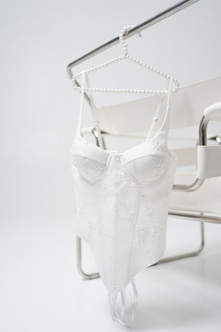 A luxurious lace mini dress with a corset base and hand-finished pearls, creating a festive and refined silhouette