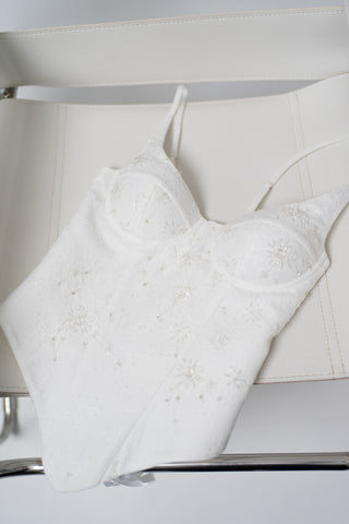 A luxurious lace mini dress with a corset base and hand-finished pearls, creating a festive and refined silhouette