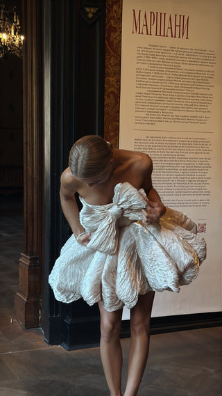 Short wedding dress with a corset top, a striking diagonal bow, and a flirty skirt made of crinkled fabric