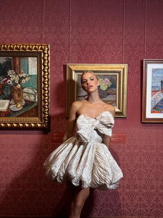 Short wedding dress with a corset top, a striking diagonal bow, and a flirty skirt made of crinkled fabric