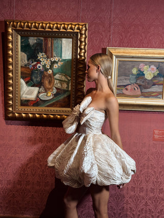 Short wedding dress with a corset top, a striking diagonal bow, and a flirty skirt made of crinkled fabric